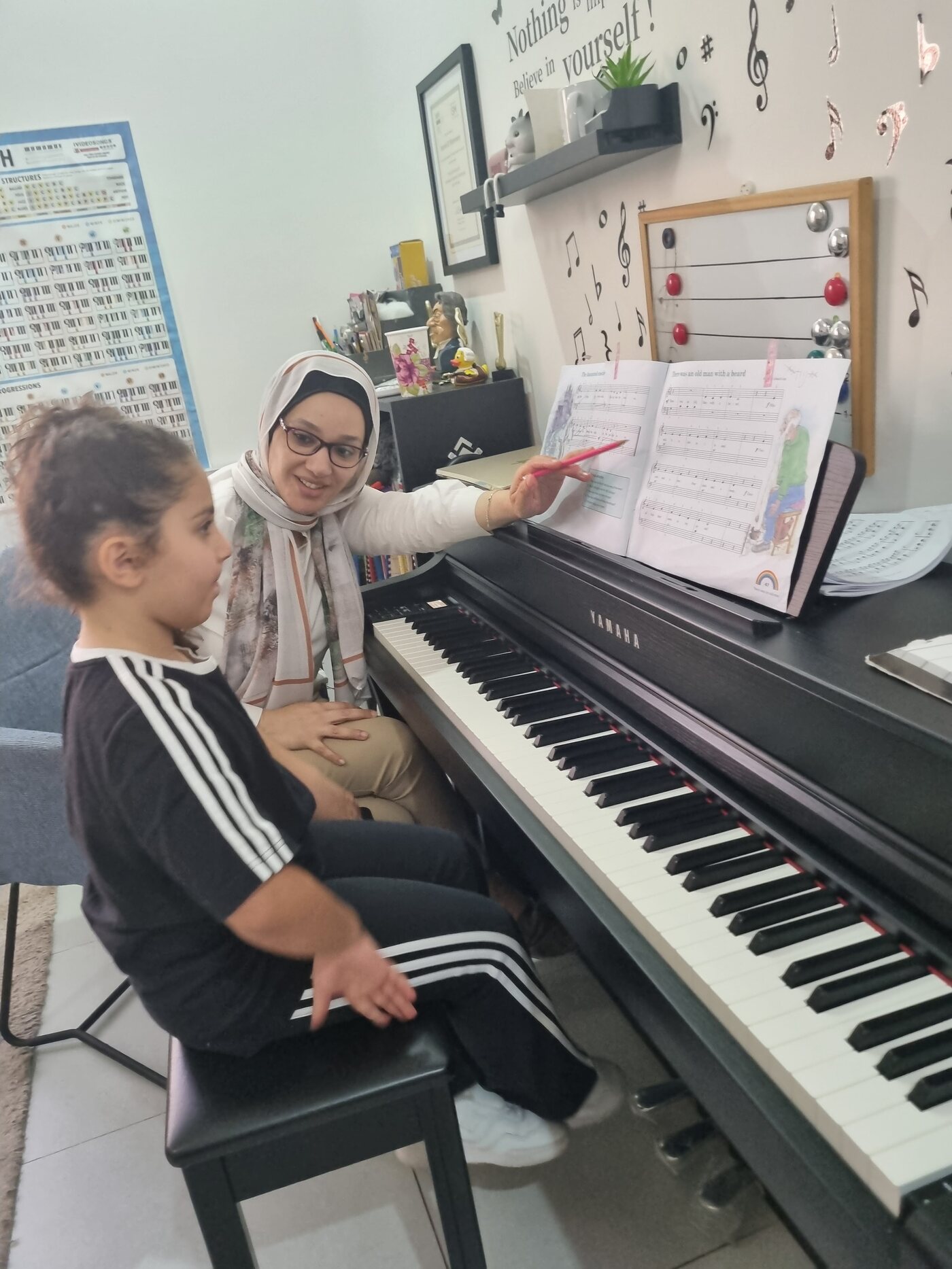 Yasmin Shennawy pointing at the music while a student sits at the keyboard