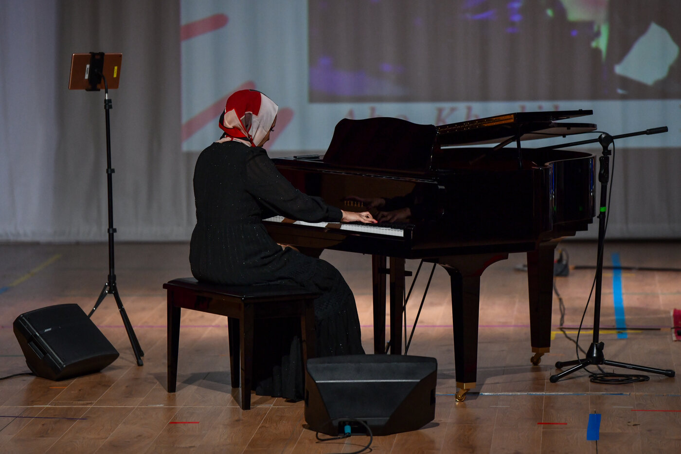 Wide view of Yasmin Shennawy performing at the grand piano on stage
